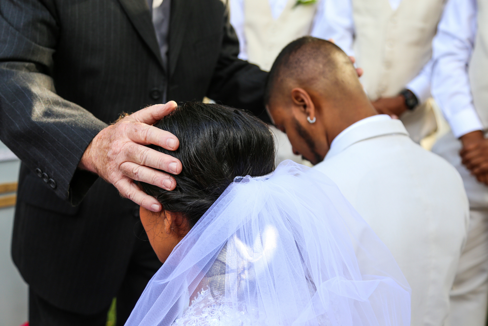 Mixed race bridal couple get blessing from priest on their wedding day