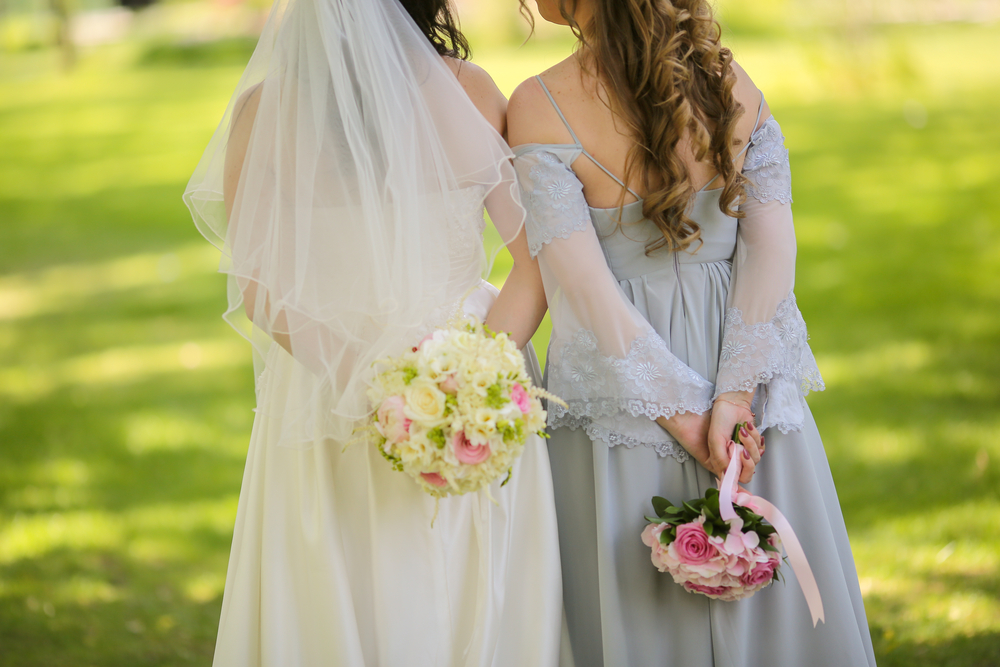 back view of bride and maid of honor holding flowers