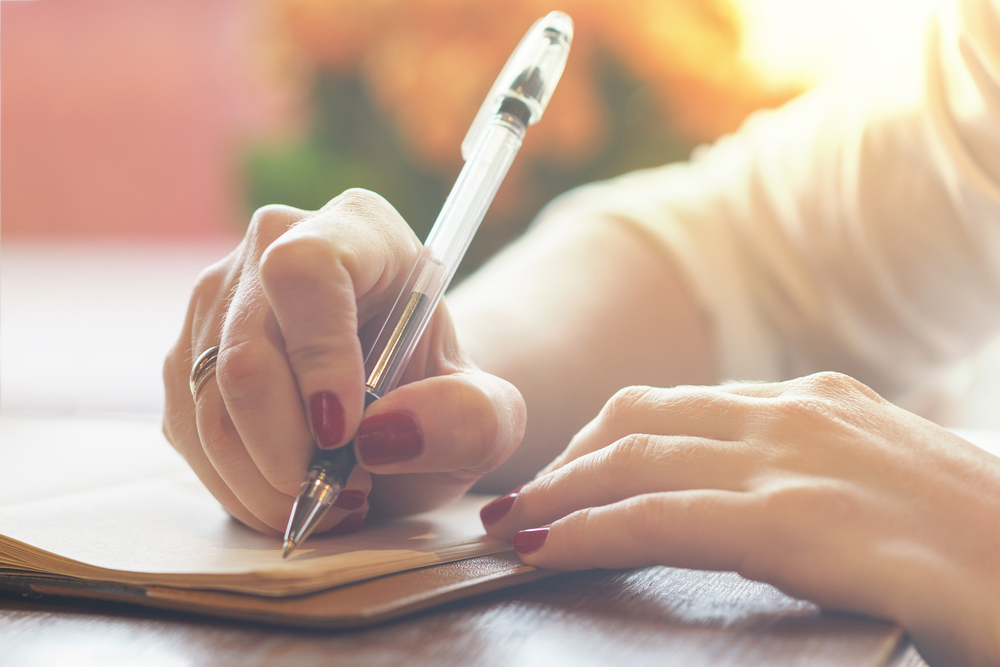 close up of woman's hand writing on a notebook