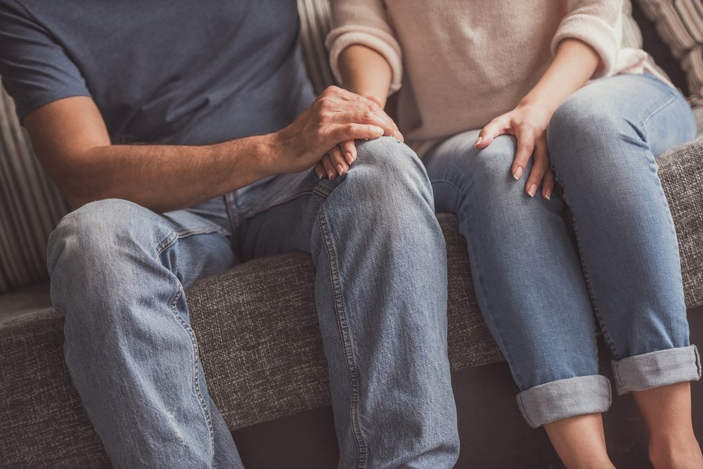 cropped image of couple talking and holding hands