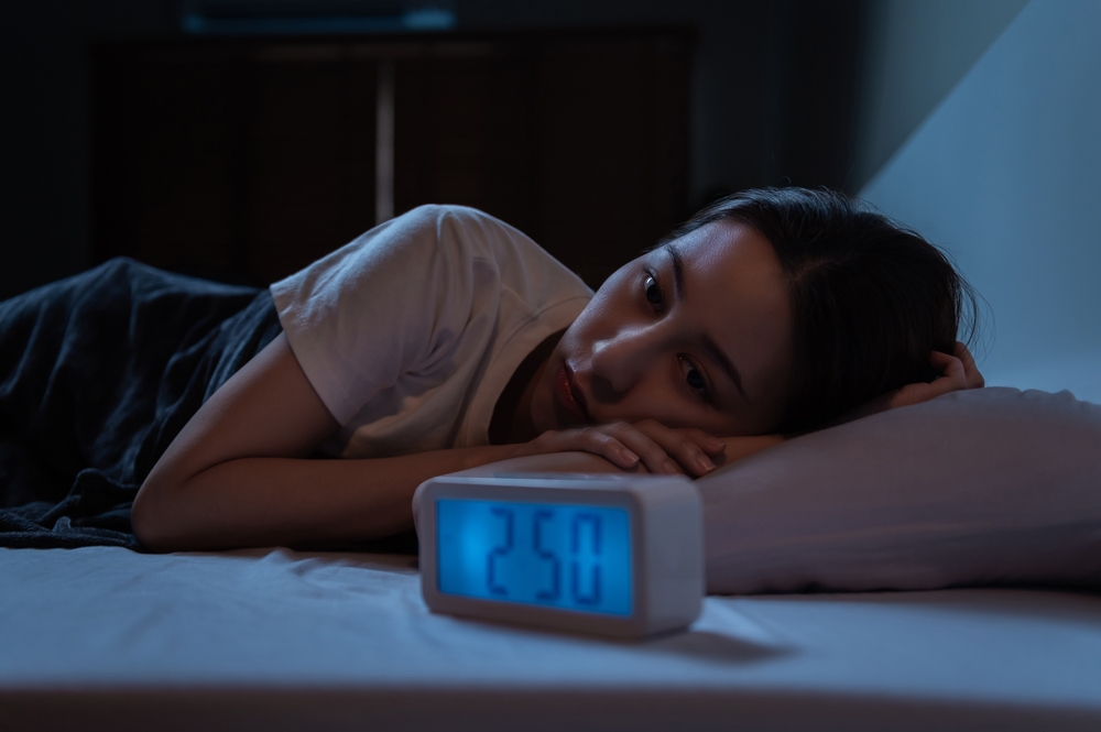 young Asian woman can't sleep with clock