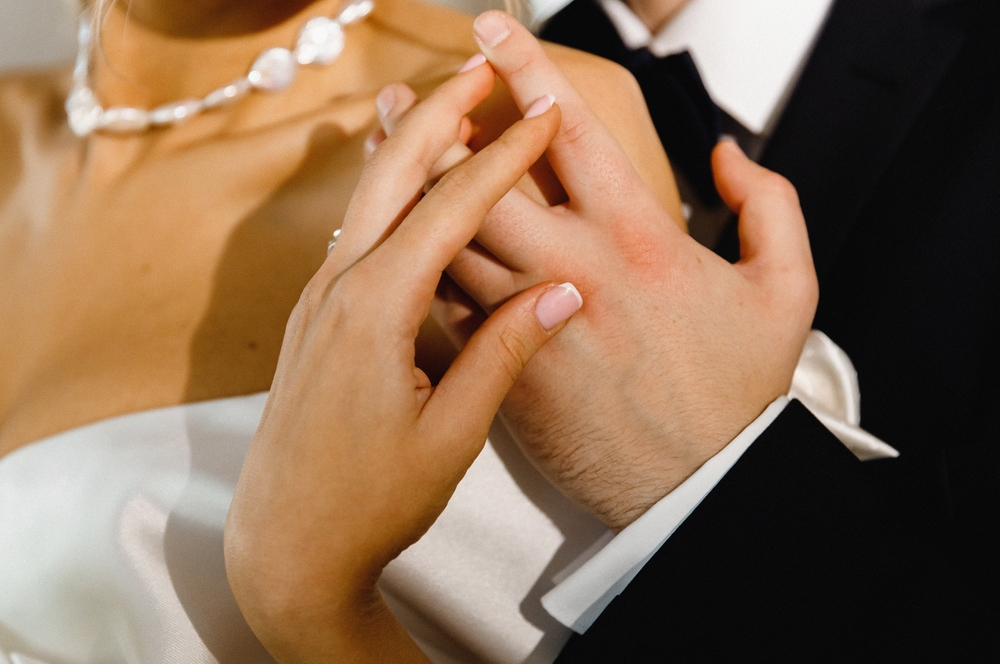 Close-up of groom's hand holding bride's hand