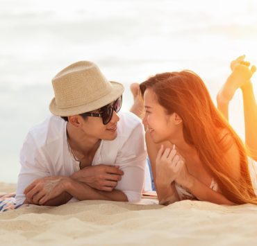 asian newly wed lying on beach during mini moon