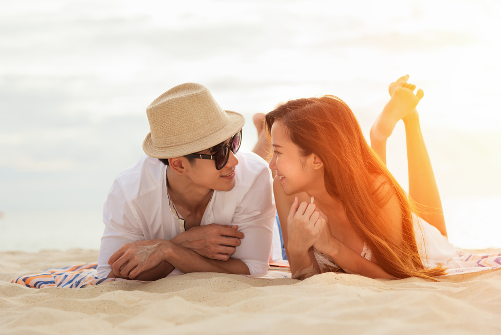 asian newly wed lying on beach during mini moon