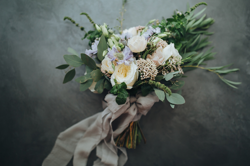 wedding bouquet of white, blue, pink flowers and greenery, decorated with long silk ribbon