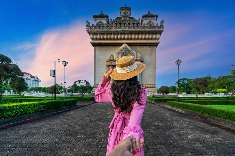 woman holding man's hand and leading him to Patuxai in Vientiane, Laos