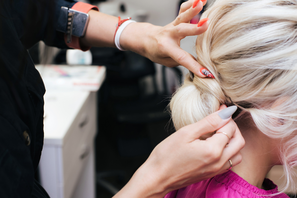 hands of a professional hairdresser make a low bun hairstyle