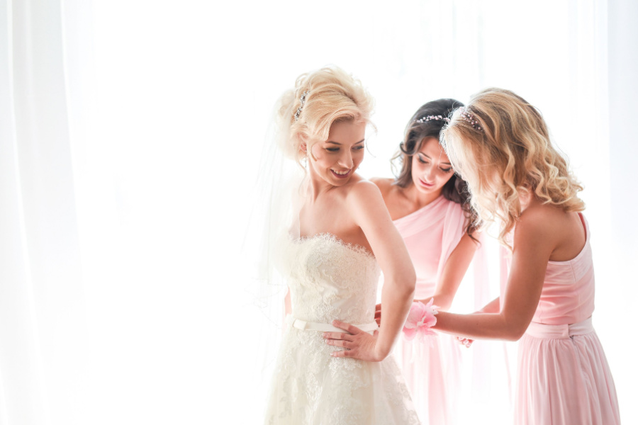 bridesmaids helping the bride with her gown
