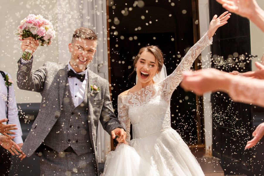 married couple being thrown with rose petals as they exit the church