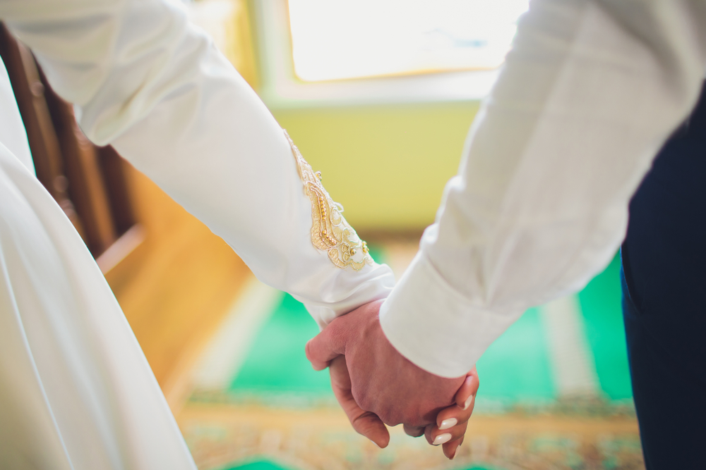 close up shot of bride and groom holding hands on traditional wedding