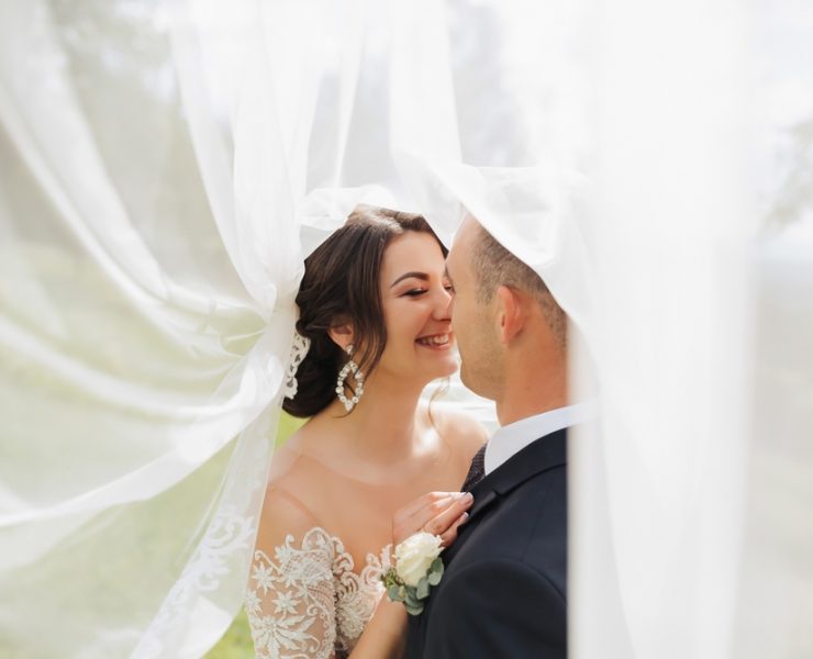 groom and bride inside of a veil