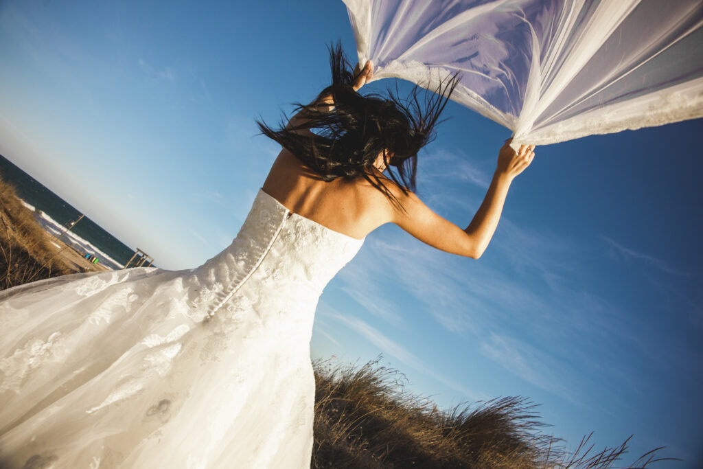 a bride holding her veil against the wind