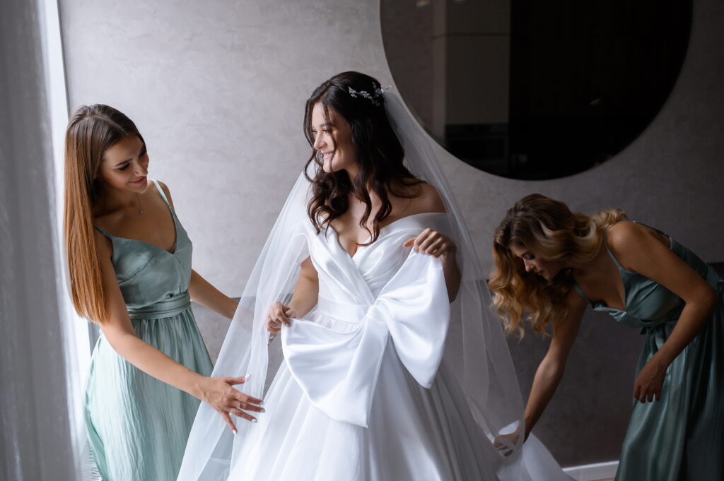 the bridesmaids fixing the bride’s gown and veil before the wedding ceremony.