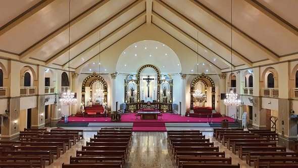 The interior of a majestic church with a golden ornate altar, intricate ceiling murals, and warm lighting.