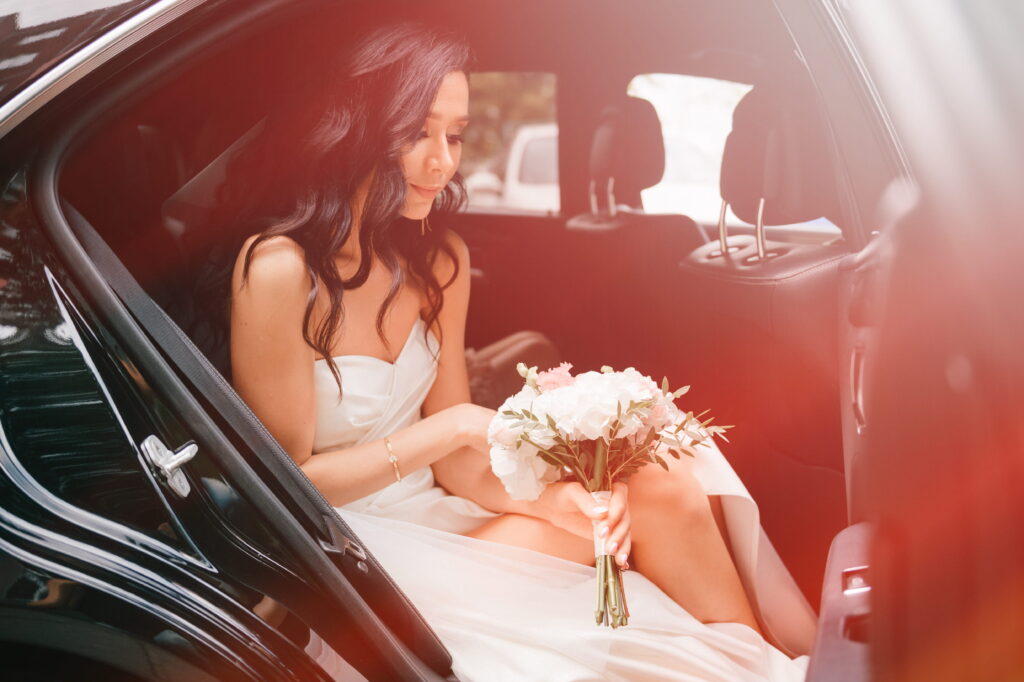 a bride with her bouquet preparing to step out of the bridal car.