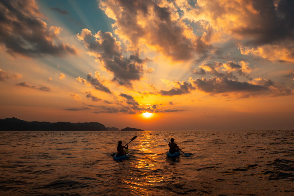 A couple paddling in kayaks in the sunset